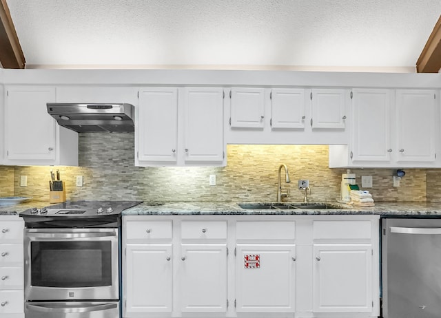 kitchen featuring appliances with stainless steel finishes, backsplash, light stone counters, white cabinets, and sink