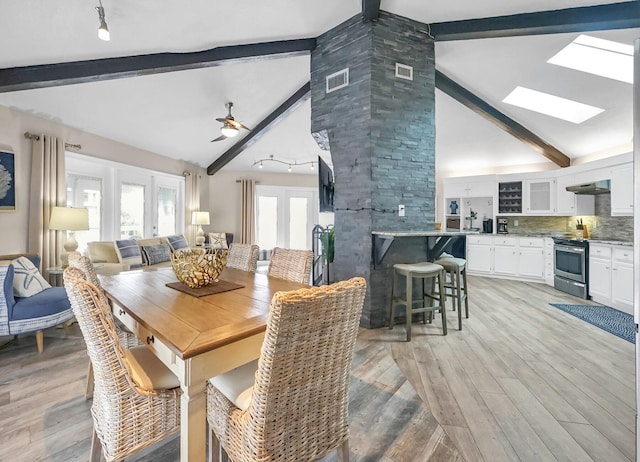 dining room with a skylight, high vaulted ceiling, ceiling fan, and beamed ceiling