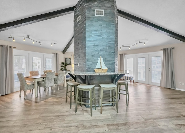 kitchen with light hardwood / wood-style flooring, a breakfast bar area, french doors, track lighting, and light stone countertops