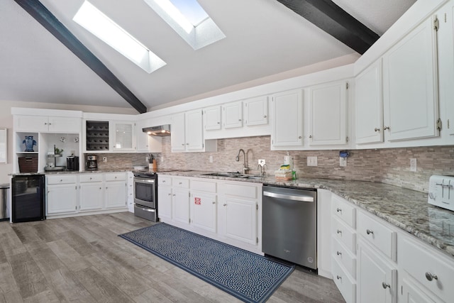 kitchen featuring white cabinets, sink, light hardwood / wood-style floors, vaulted ceiling with skylight, and stainless steel appliances