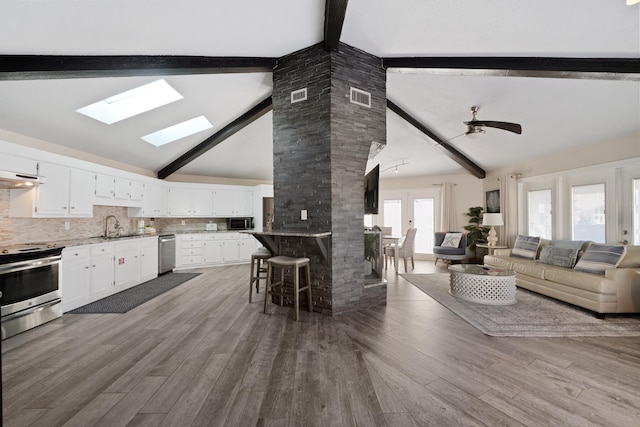 kitchen with beamed ceiling, white cabinets, and a kitchen bar