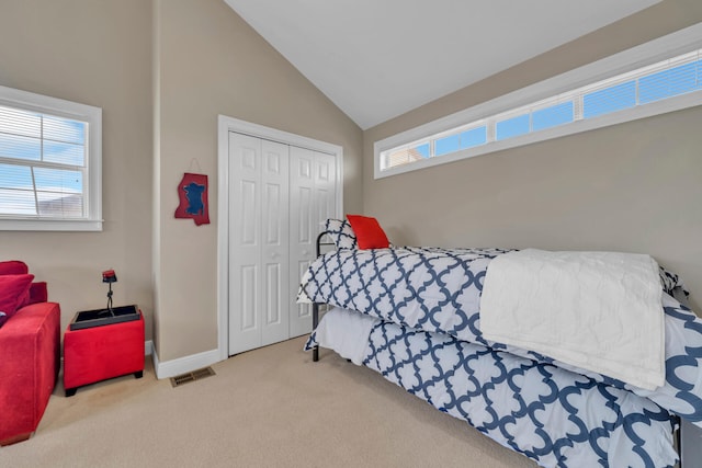 bedroom featuring light carpet, vaulted ceiling, and a closet