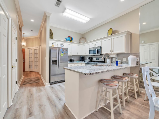 kitchen featuring appliances with stainless steel finishes, light hardwood / wood-style flooring, kitchen peninsula, backsplash, and light stone countertops