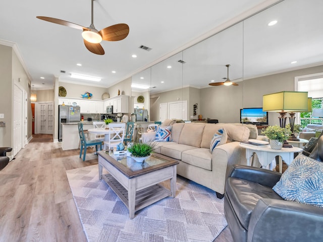 living room featuring light hardwood / wood-style floors, ceiling fan, and crown molding