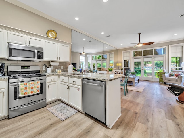 kitchen with plenty of natural light, kitchen peninsula, light wood-type flooring, and stainless steel appliances