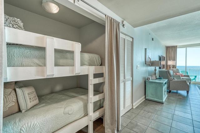 tiled bedroom featuring a water view and a closet