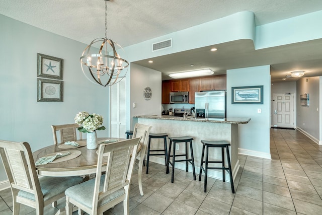 dining room with a textured ceiling, light tile floors, and a notable chandelier