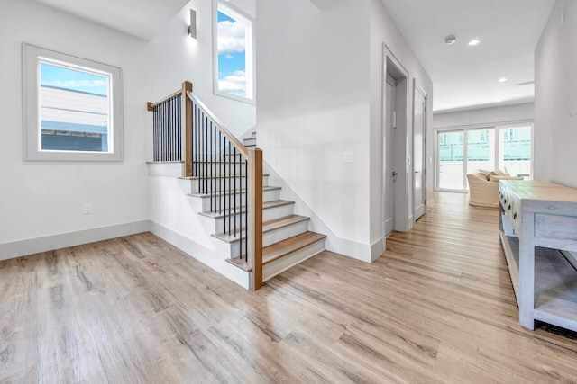 stairs with light hardwood / wood-style flooring and a wealth of natural light