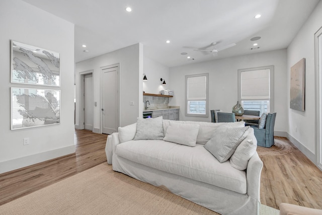 living room featuring sink, ceiling fan, and light hardwood / wood-style floors