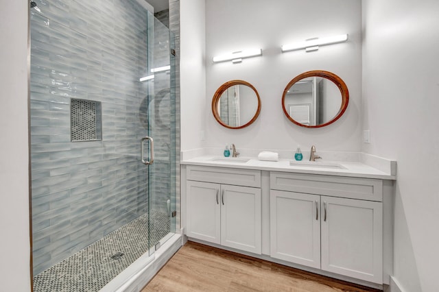 bathroom with walk in shower, wood-type flooring, large vanity, and double sink