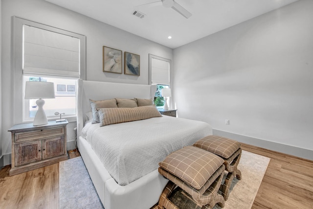 bedroom with ceiling fan, light hardwood / wood-style floors, and multiple windows