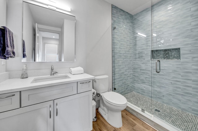 bathroom with walk in shower, wood-type flooring, toilet, and vanity