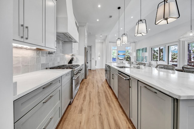 kitchen featuring appliances with stainless steel finishes, custom exhaust hood, tasteful backsplash, light wood-type flooring, and a large island