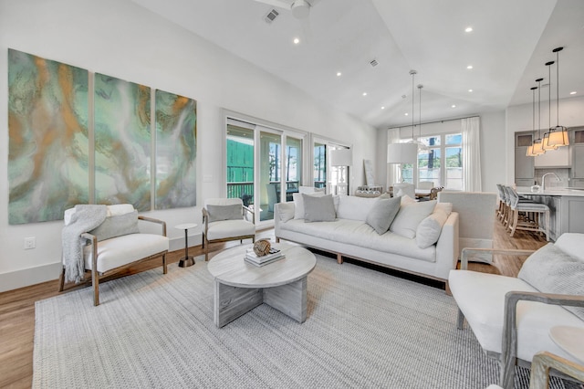 living room featuring light hardwood / wood-style flooring, sink, and lofted ceiling