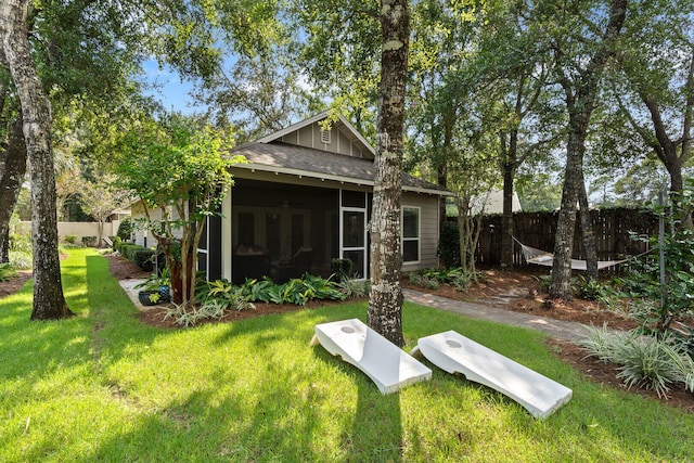 back of property with a sunroom and a lawn