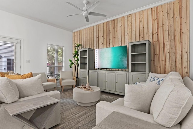 living room featuring ornamental molding, ceiling fan, and wood walls