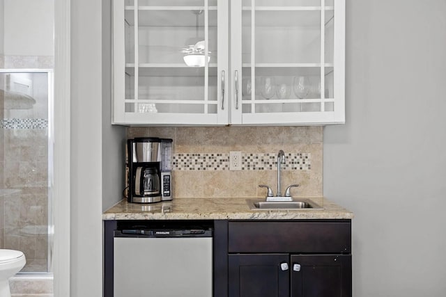 bar with dark brown cabinetry, sink, dishwashing machine, and light stone counters