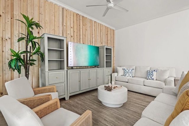 living room with wood walls, ceiling fan, crown molding, and light wood-type flooring