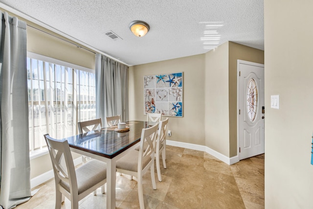 tiled dining space featuring a healthy amount of sunlight and a textured ceiling