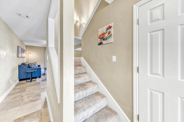 stairway featuring light tile flooring and a textured ceiling