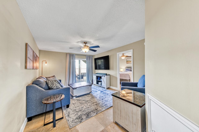 living room with ceiling fan, light tile floors, and a textured ceiling