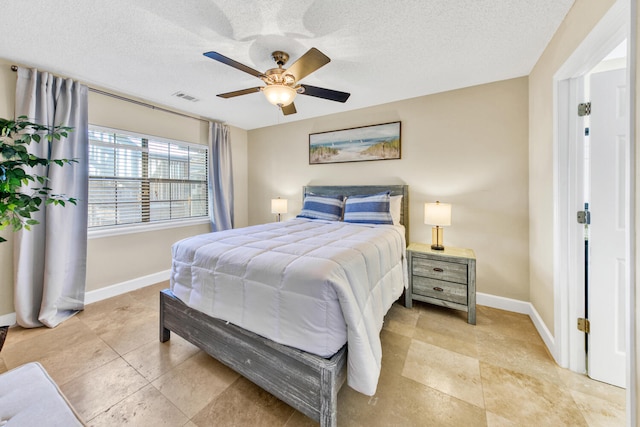 bedroom featuring a textured ceiling, ceiling fan, and light tile flooring