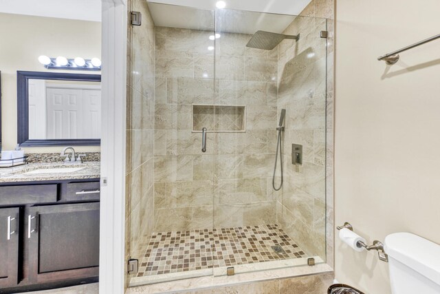 bathroom featuring oversized vanity, toilet, and a shower with door