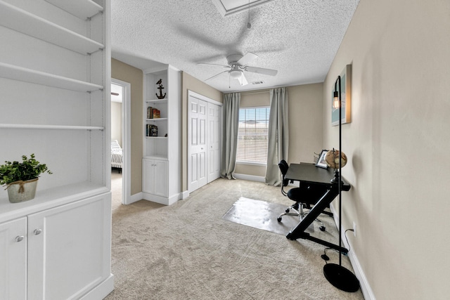 office featuring light carpet, ceiling fan, and a textured ceiling