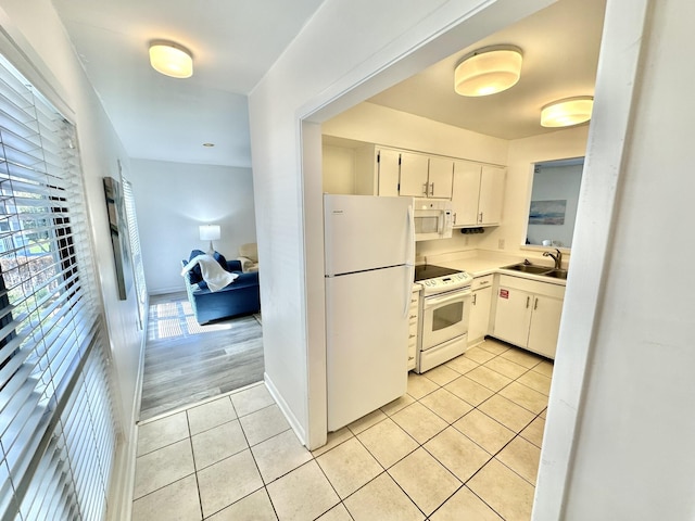 kitchen with white cabinets, white appliances, sink, and light tile patterned floors