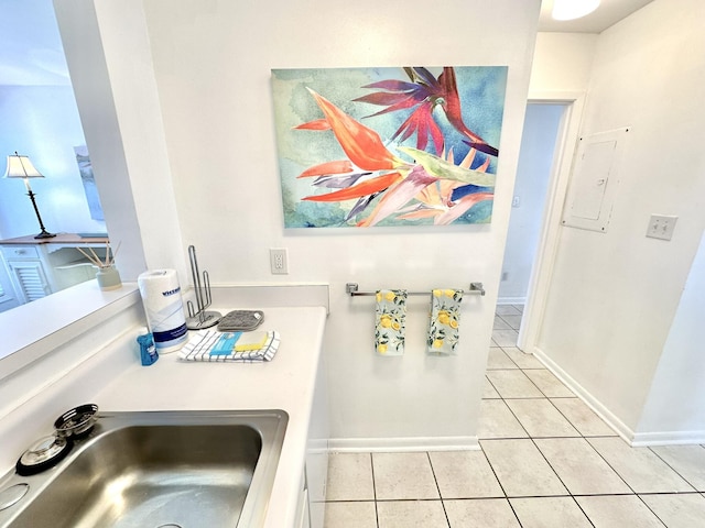 kitchen featuring electric panel, sink, and light tile patterned flooring