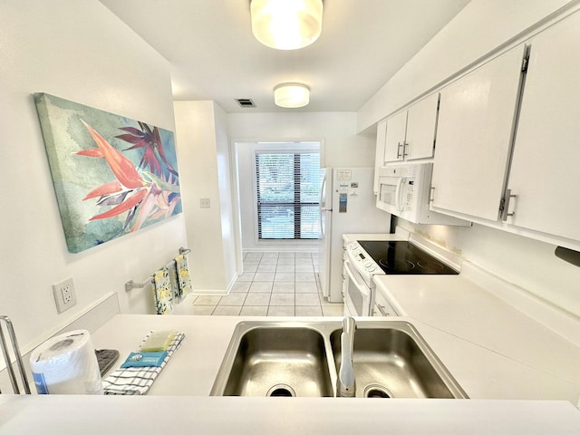 kitchen with white cabinetry, sink, light tile patterned floors, and white appliances