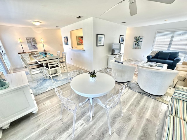 living room featuring light wood-type flooring, ceiling fan, and a healthy amount of sunlight