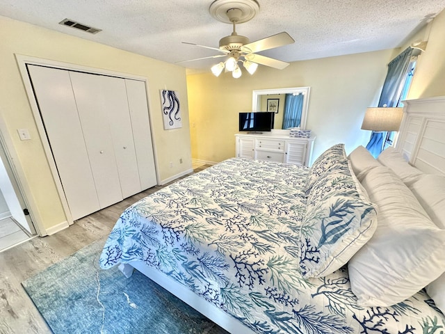 bedroom featuring ceiling fan, light wood-type flooring, a textured ceiling, and a closet