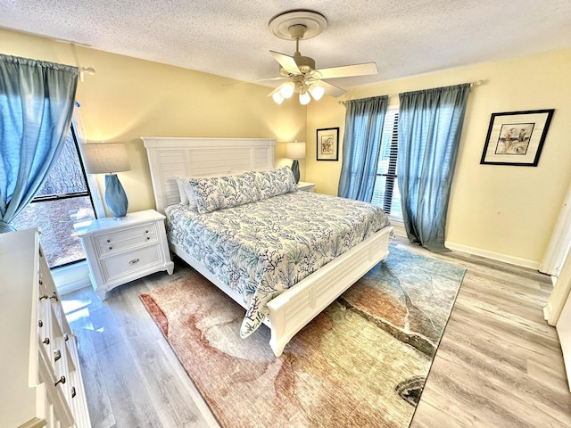 bedroom with a textured ceiling, light hardwood / wood-style flooring, and ceiling fan