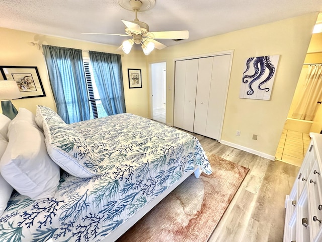 bedroom with light hardwood / wood-style flooring, ceiling fan, a textured ceiling, connected bathroom, and a closet