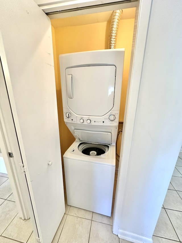 laundry area with light tile patterned floors and stacked washer and dryer