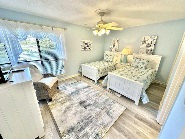 bedroom with a textured ceiling, light hardwood / wood-style flooring, and ceiling fan