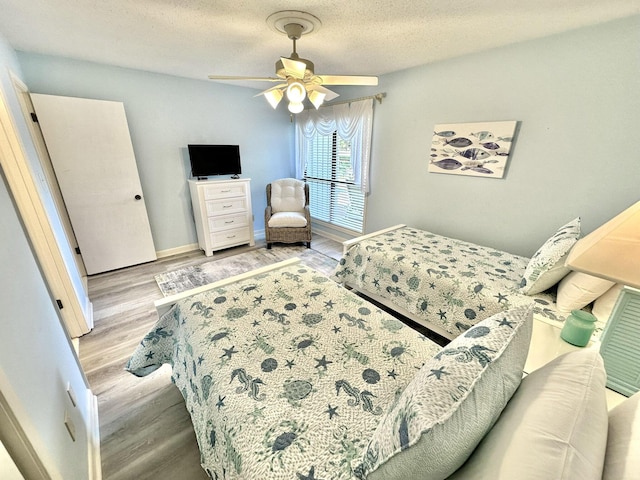 bedroom featuring ceiling fan, a textured ceiling, and light hardwood / wood-style flooring