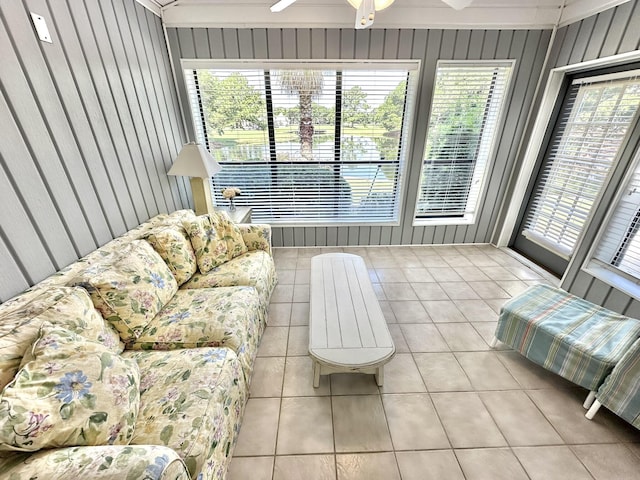 living room featuring light tile patterned floors, ceiling fan, and wood walls