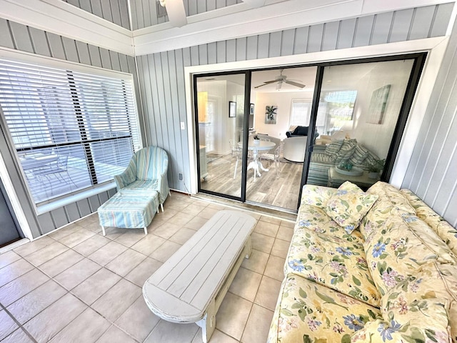 interior space with light tile patterned floors, ceiling fan, and wooden walls