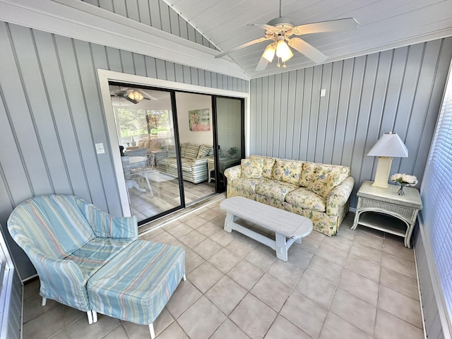 living room with ceiling fan, light tile patterned flooring, lofted ceiling, and wooden walls