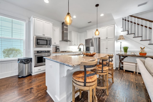 kitchen featuring white cabinets, appliances with stainless steel finishes, wall chimney range hood, and dark hardwood / wood-style floors