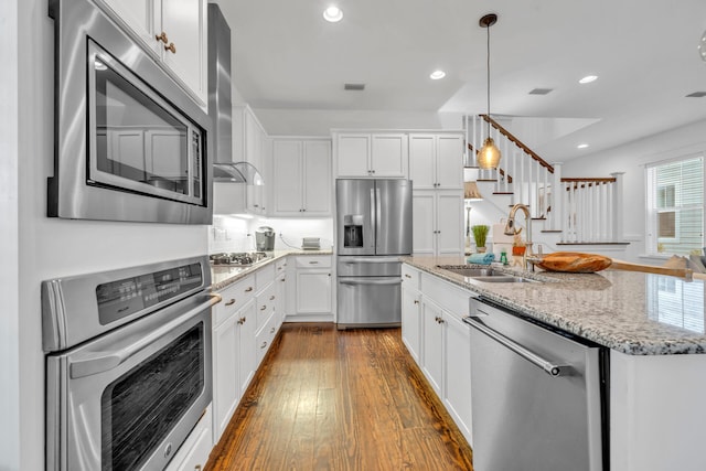 kitchen with white cabinets, dark wood-type flooring, stainless steel appliances, sink, and light stone counters