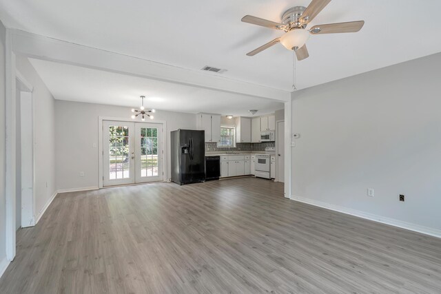 unfurnished living room with light wood-type flooring, french doors, and ceiling fan with notable chandelier