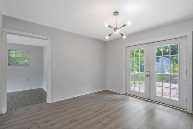 spare room featuring a textured ceiling, french doors, a chandelier, and dark hardwood / wood-style floors