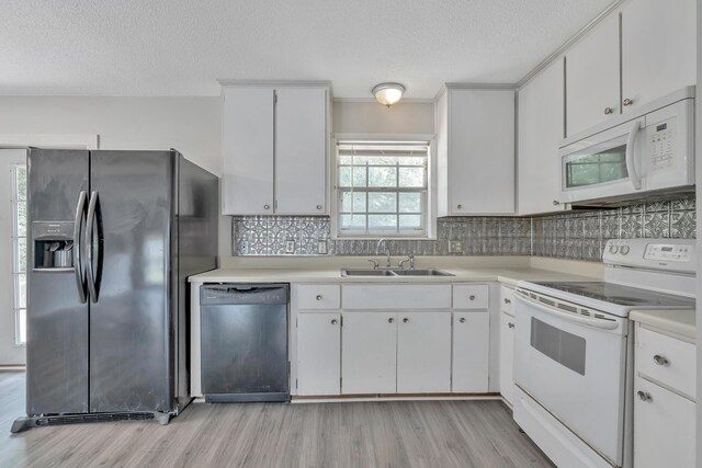 kitchen with a textured ceiling, sink, white cabinets, and white appliances