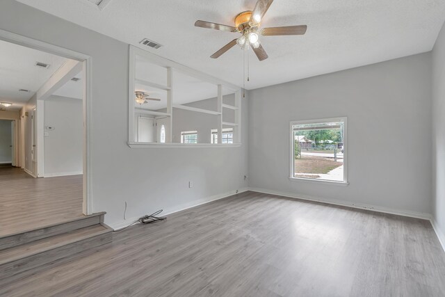 unfurnished room featuring ceiling fan, light hardwood / wood-style floors, and a textured ceiling