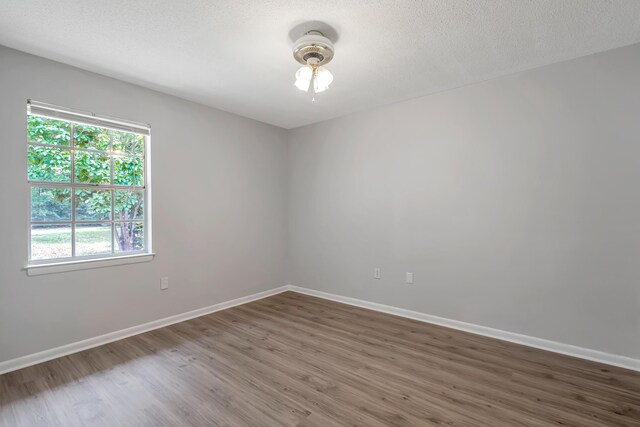 unfurnished room with a textured ceiling and dark hardwood / wood-style floors