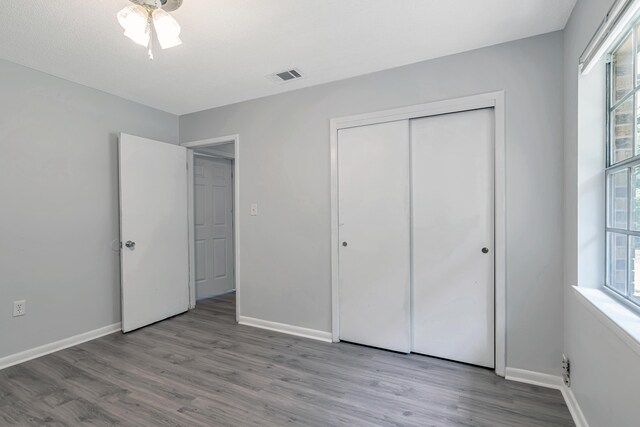 unfurnished bedroom with light hardwood / wood-style flooring, a closet, and ceiling fan