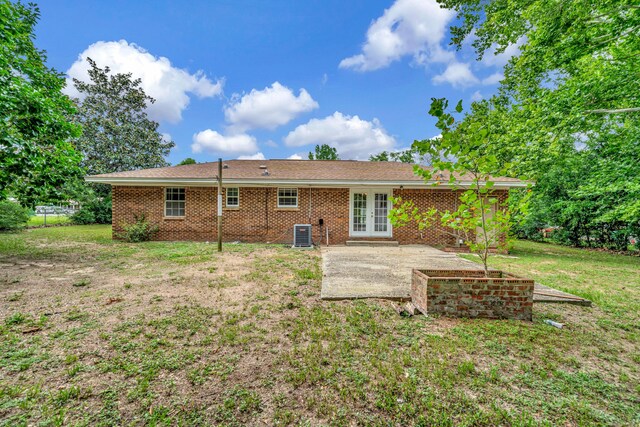 rear view of house with french doors, a patio, and a lawn